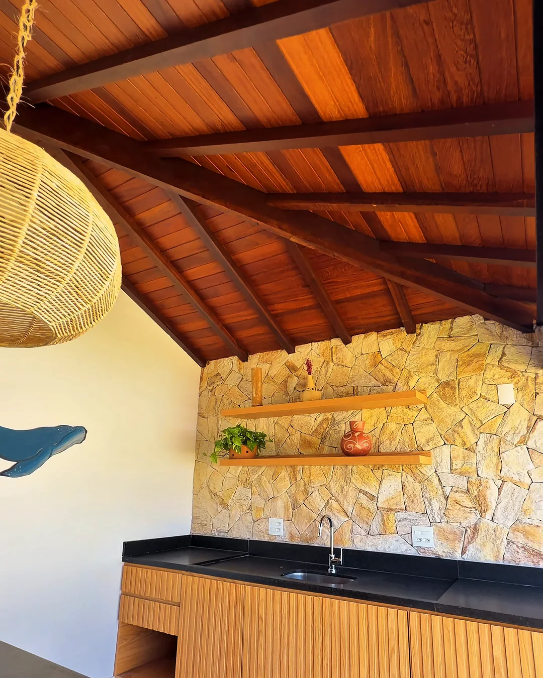 Área gourmet da casa decorada, com bancada e parede de pedra