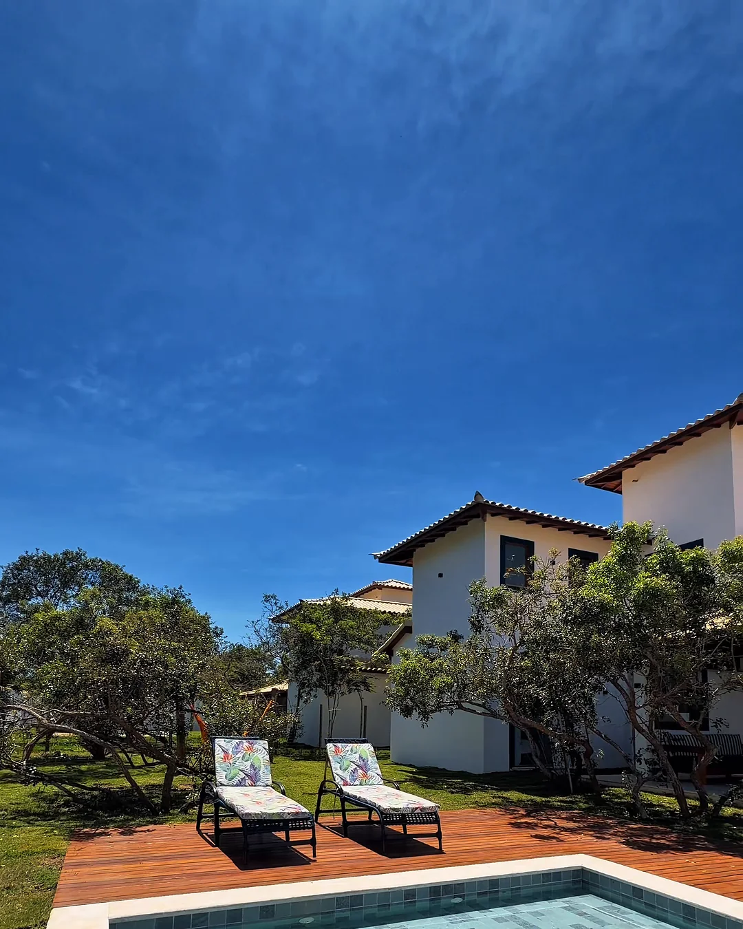 Piscina com deck de madeira e as casas ao fundo