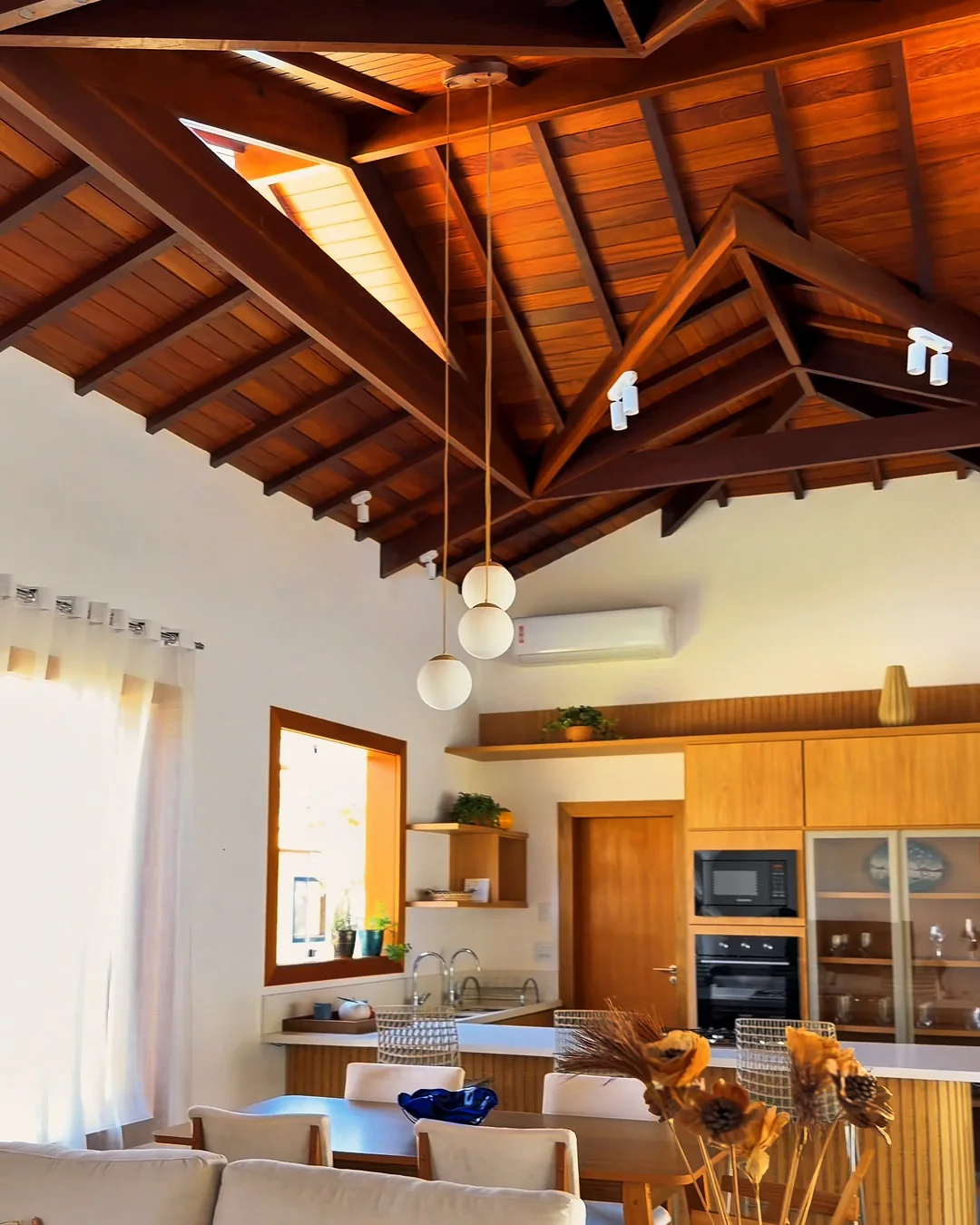 Sala e cozinha integradas da casa decorada, com forro de madeira
